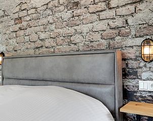 Sfeervol bed in Vakantiehuisje in Een, Noord Drenthe, met bakstenen muur en industrile lampen.