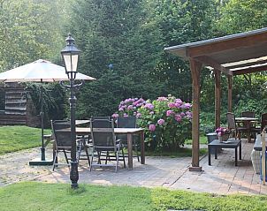 Terras van Huisje in Spijkerboor, Noord Drenthe, met houten eettafel en kleurrijke bloemen.