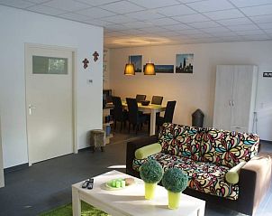 Stijlvolle woonkamer van bungalow Rendez vous in Zuidlaren, Noord Drenthe, met kleurrijke bank en eethoek.