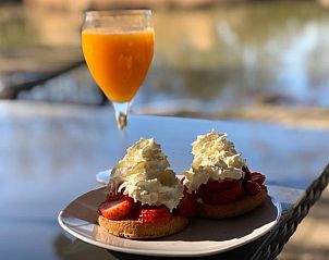 Geniet van een ontbijt op het terras van Vakantiehuisje in Eext, gelegen in het serene Noord Drenthe, met vers fruit en sinaasappelsap.
