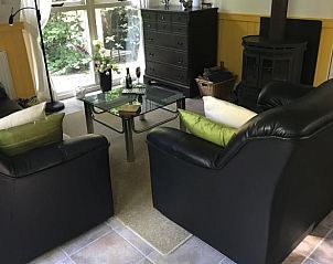 Gezellige woonkamer in Vakantiehuis in Norg, Noord Drenthe, met comfortabele zithoek en houtkachel, ideaal voor ontspanning.