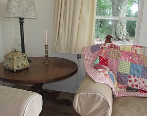 Knusse hoek in de woonkamer van Vakantiehuisje in Midlaren, Noord Drenthe, met kleurrijke quilt en uitzicht op de tuin.