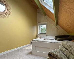 Slaapkamer met dakraam en stoel in Vakantiehuisje in Midlaren, Noord Drenthe, Drenthe.