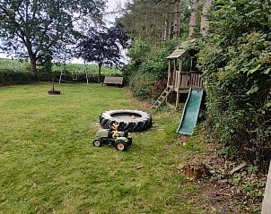 Gezellige woonkamer van DG588 vakantiehuis in Midlaren, Drenthe, met kleurrijke stoelen en een ronde eettafel.