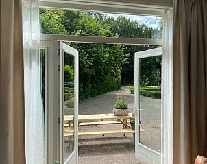 Uitzicht vanuit de woonkamer van Huisje in Tynaarlo, Noord Drenthe, met openslaande deuren naar het terras.