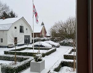 Winterse sfeer bij Huisje in Tynaarlo, Noord Drenthe, met besneeuwde tuin en vlag.