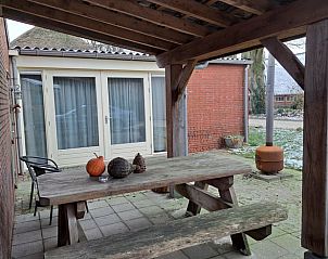 Overdekt terras in Vakantiehuis in Zeegse, Drenthe met rustieke houten tafel.