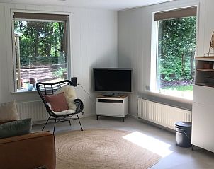 Lichte woonkamer in Huisje in Steenbergen, vakantiehuis in Drenthe met uitzicht op groene tuin en serene omgeving.