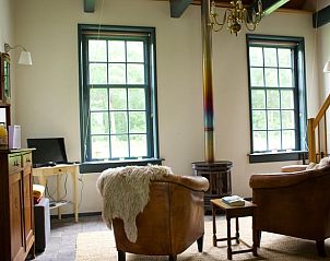 Lichte woonkamer van Vakantiehuis in Veenhuizen, Noord Drenthe met grote ramen en sfeervolle inrichting.