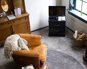 Knusse zithoek in Vakantiehuis in Veenhuizen, Noord Drenthe met leren stoel en houten kast.