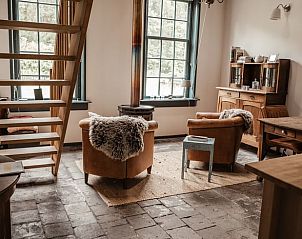 Ruime binnenruimte van Vakantiehuisje in Veenhuizen, Drenthe, met houten trap en comfortabele zithoek.