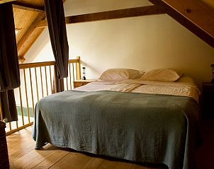 Slaapkamer in Vakantiehuisje in Veenhuizen, Drenthe, met rustieke houten balken en comfortabel bed.