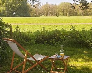 Ontspannen in de tuin van Vakantiehuisje in Veenhuizen, Noord Drenthe, met uitzicht op groene velden.