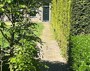 Toegangspad naar Vakantiehuisje in Veenhuizen, Noord Drenthe, met groene heggen en stenen pad.