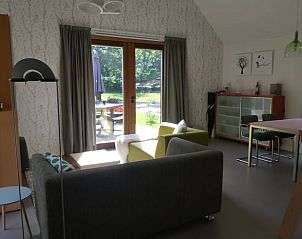 Gezellige woonkamer van Huisje in Bunne, vakantiehuis in Noord Drenthe, met uitzicht op groene tuin door openslaande deuren.