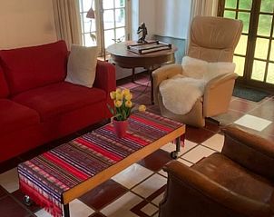 Lichte woonkamer in Huisje in Zuidlaarderveen, vakantiehuis met rood bankstel in Noord Drenthe, Drenthe.