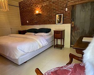 Knusse slaapkamer in Huisje in Buinerveen, vakantiehuis in Noord Drenthe, met bakstenen muur en houten meubels.