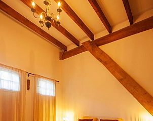 Hoge houten balken in Huisje in Buinerveen, vakantiehuis in Drenthe, geven karakter aan de slaapkamer.