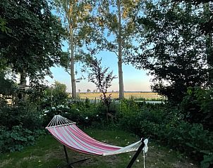Ontspannen hangmat in de tuin van Huisje in Buinerveen, vakantiehuis in Drenthe, met uitzicht op de velden.