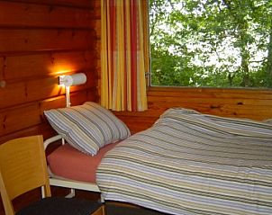 Knusse eenpersoonsslaapkamer in Finse bungalow, Meppen, Drenthe, met groot raam en natuurlijke lichtinval.