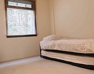 Terras van DG357 vakantiehuis in Meppen, Drenthe met houten stoelen en groene omgeving.