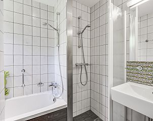 Dining area and kitchen in Aelderholt 6-person children's bungalow in Aalden, Southeast Drenthe with spacious table and modern appliances.