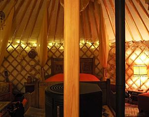 Gezellige binnenruimte van de yurt bij Vakantiehuisje in Emmen, Drenthe, met sfeerverlichting.