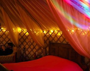 Sfeervolle slaapkamer in de yurt bij Vakantiehuisje in Emmen, Drenthe, met kleurrijke verlichting.
