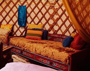 Comfortabele bank in de yurt bij Vakantiehuisje in Emmen, Drenthe, met kleurrijke kussens.