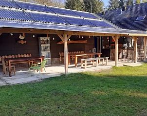 Ruime veranda bij Vakantiehuisje in Emmen, Drenthe, met houten zitplaatsen.