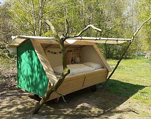 Vakantiehuis in Emmen biedt een charmant houten bed met uitzicht op de Drentse bossen.