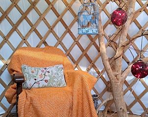 Vakantiehuis in Emmen, uitnodigende leeshoek in de yurt van de vakantiewoning in Zuidoost Drenthe, met comfortabele stoel.