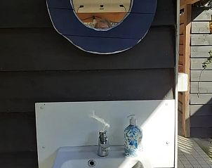 Vakantiehuis in Emmen, stijlvolle wastafel in de buitenruimte van de vakantiewoning in Zuidoost Drenthe, met ronde spiegel.