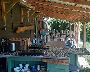 Vakantiehuis in Emmen, gezellige buitenkeuken van de vakantiewoning in Zuidoost Drenthe, met lange tafel en stoelen.