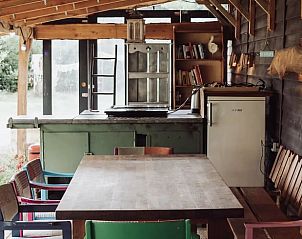 Vakantiehuis in Emmen, ruime eetruimte in de buitenkeuken van de vakantiewoning in Zuidoost Drenthe, met kleurrijke stoelen.