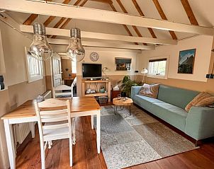 Knusse woonkamer van Vakantiehuis in Dalen, Zuidoost Drenthe, met houten balken en comfortabele zithoek.