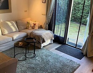 Gezellige woonkamer van Huisje in Dalen, vakantiehuis in Dalen, Drenthe, met comfortabele bank en uitzicht op groene tuin.