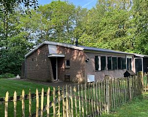 Buitenkant van Huisje in Gees, vakantieverblijf in Zuidoost Drenthe, omgeven door bomen en een houten hek.