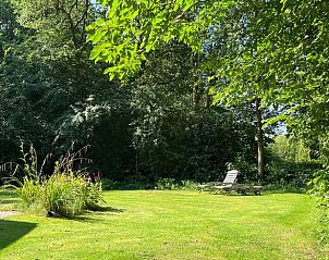 Grote tuin met ligstoelen bij Huisje in Gees, vakantieverblijf in Zuidoost Drenthe, omringd door bomen.