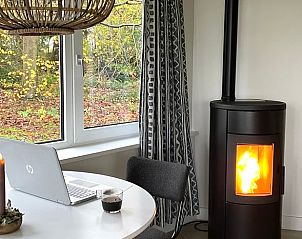 Huisje in Valthe, Drenthe, sfeervolle eethoek met houtkachel en uitzicht op herfstlandschap.