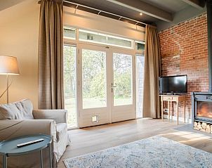 Gezellige zithoek in Huisje in Valthe, vakantiehuis in Drenthe met open haard en uitzicht op de tuin.