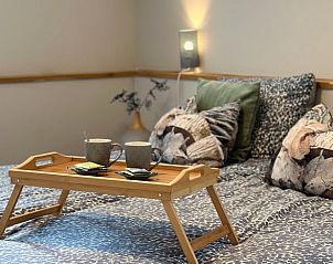 Sfeervolle slaapkamer in Vakantiehuisje in Valthe, Drenthe met comfortabele bedden en decoratieve kussens.