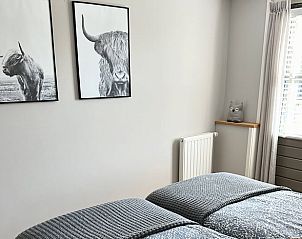 Slaapkamerdecoratie in Vakantiehuisje in Valthe, Drenthe met kunst aan de muur en gezellige sfeer.