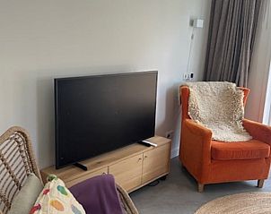 Gezellige zithoek met oranje stoel in Vakantiehuis in Schoonoord, Drenthe.