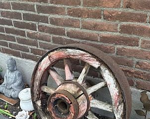 Decoratief wagenwiel bij Vakantiehuis in Schoonoord, Drenthe, met bakstenen muur.