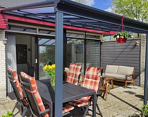 Eethoek op het terras van Huisje in Geesbrug, vakantiehuis in Geesbrug, Zuidoost Drenthe, met fleurige kussens en bloemen.