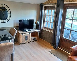 Gemtliches Wohnzimmer im Ferienhaus in Stieltjeskanaal, Sdost-Drenthe, mit rustikalen Mbeln und Blick auf die grne Umgebung.