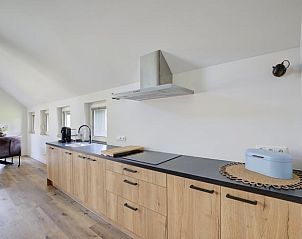Moderne keuken in Huisje in Benneveld, Zuidoost Drenthe, met houten kasten en uitzicht op de eetruimte.