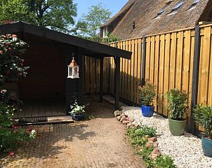 Gezellig terras bij Vakantiehuis in Benneveld, Zuidoost Drenthe, omgeven door bloemen en houten schutting.