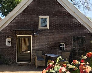 Knusse entree van Vakantiehuis in Benneveld, Zuidoost Drenthe, met rieten meubilair voor ontspanning.